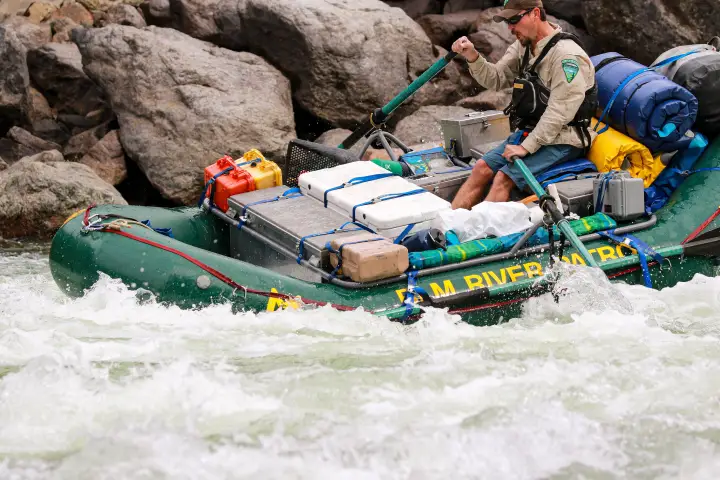 A BLM river patrol raft punching through a large wave in a rapid