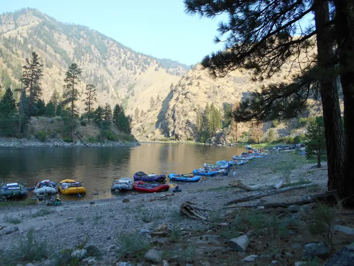 Rafts lined up on a gravel bar at Corn Creek in early morning light, canyon walls behind