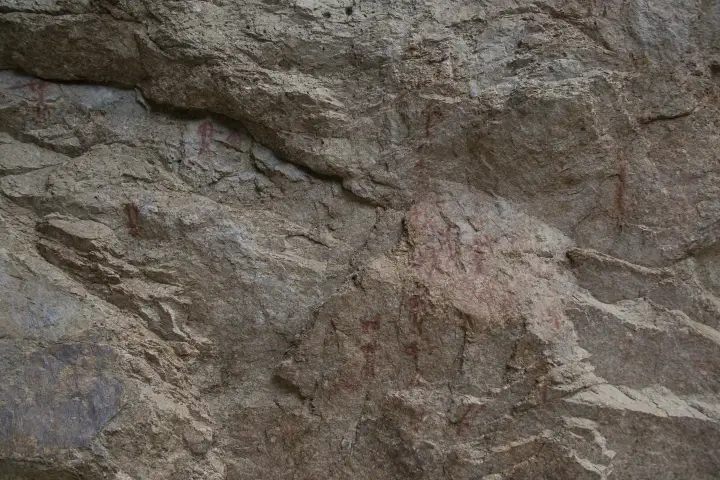 Red ochre pictograph figures on a granite wall beside the Middle Fork